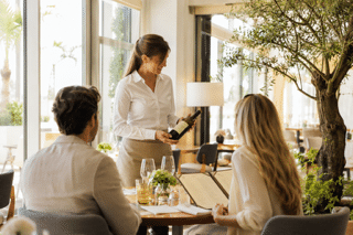 Servicekraft im aktiven Verkauf empfiehlt einem Gast einen Wein